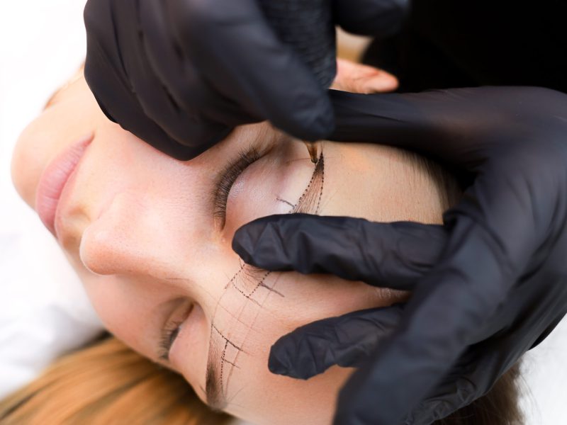 the permanent makeup artist stretches the skin in the area of the eyebrows to perform the tattoo